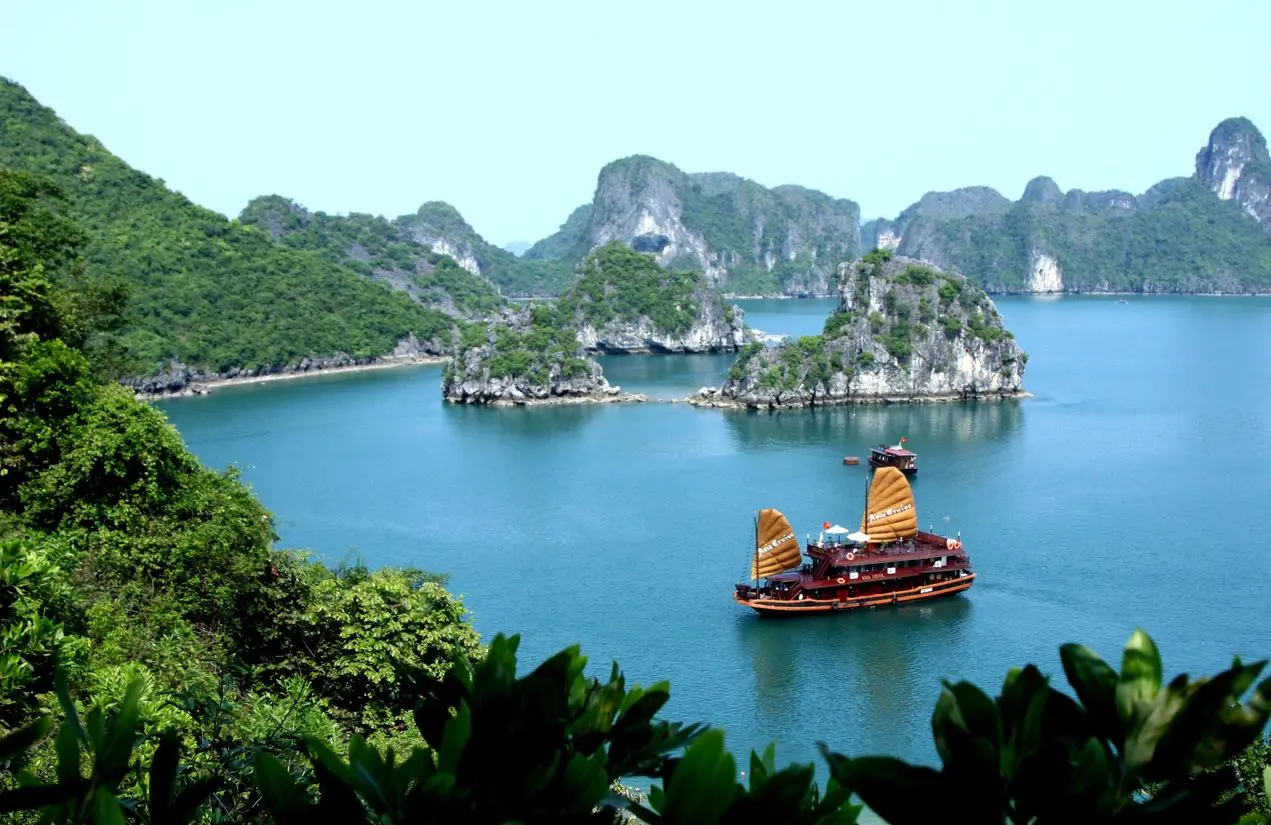 Traditional boat sailing in a scenic bay surrounded by limestone islands.