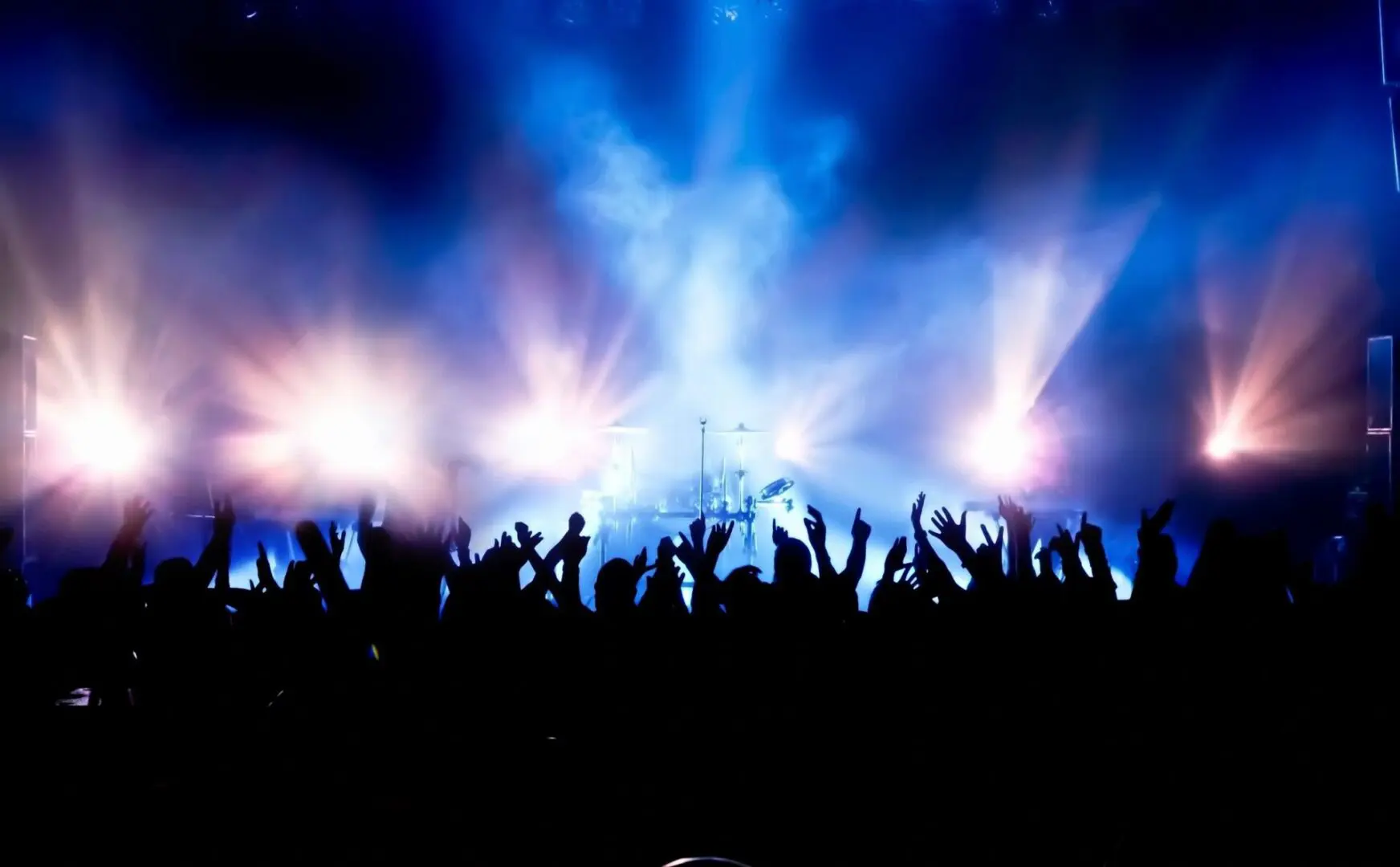 Crowd enjoying a vibrant concert with bright stage lights.