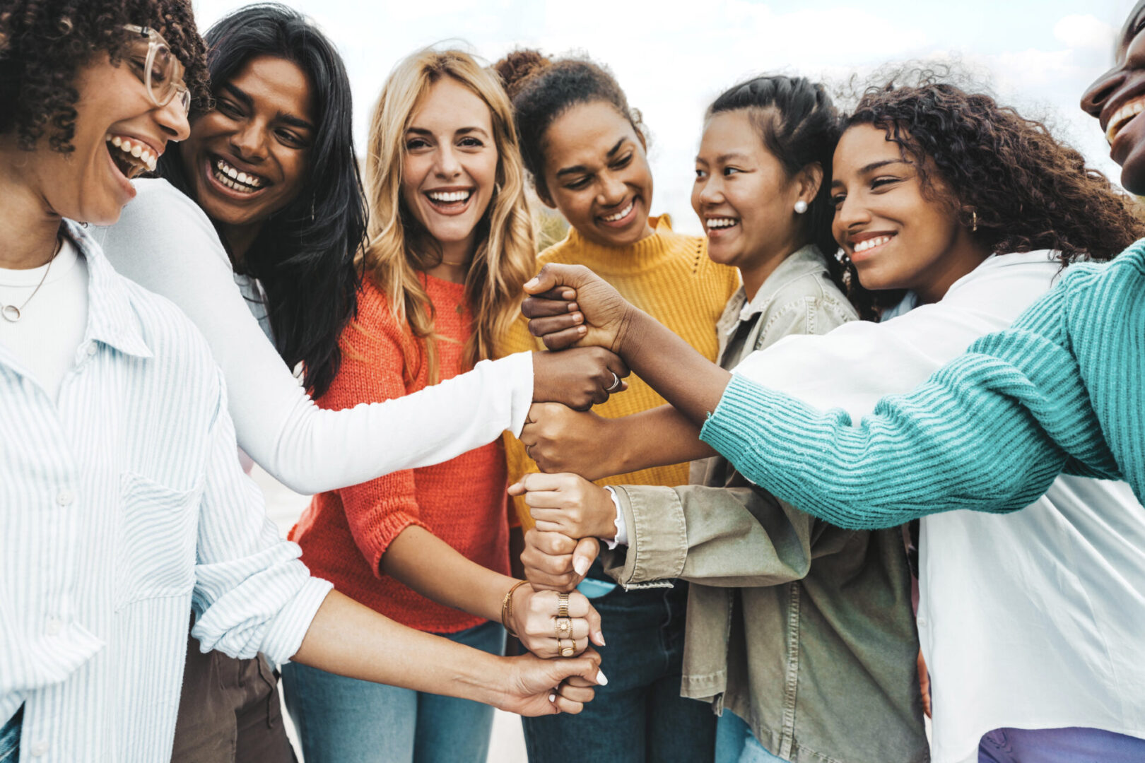 Group of diverse women smiling and holding a bottle of champagne.