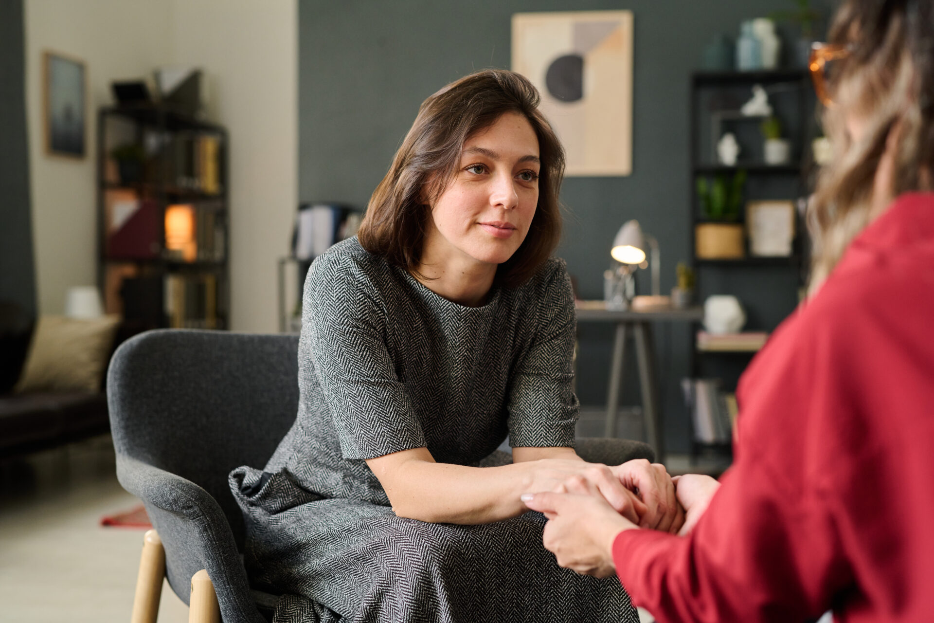 Woman attentively listening and holding hands with another person.