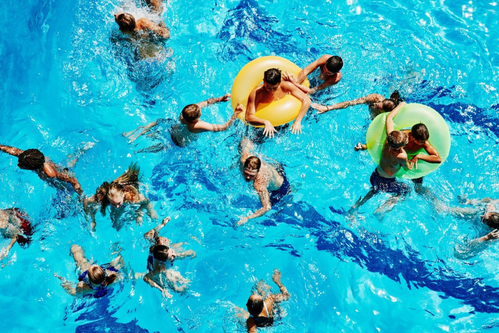 Children playing and swimming in a pool with colorful floaties.