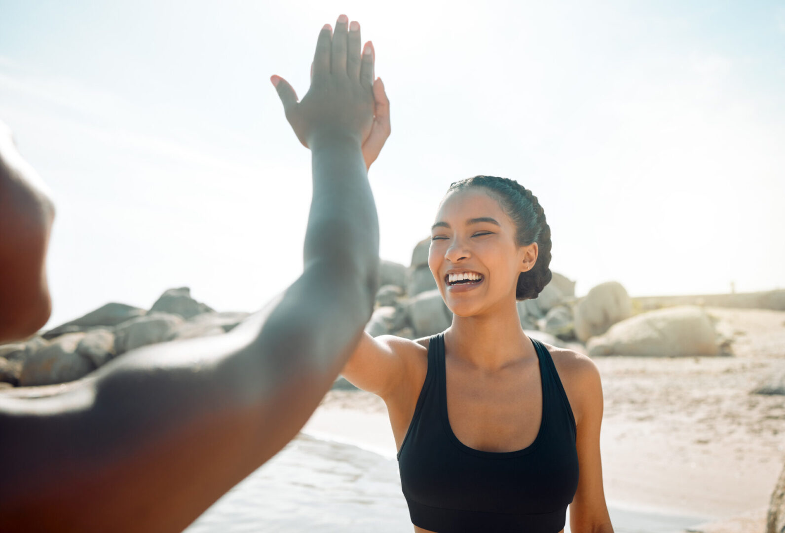 Two people sharing a joyful high-five at the beach.